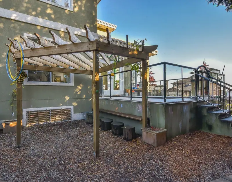 A covered pergola deck with wooden stump seating and planters