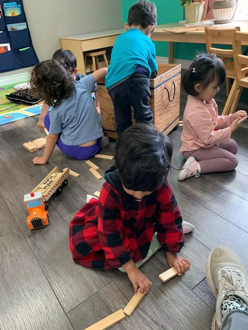 Children building with wooden blocks together on the classroom rug