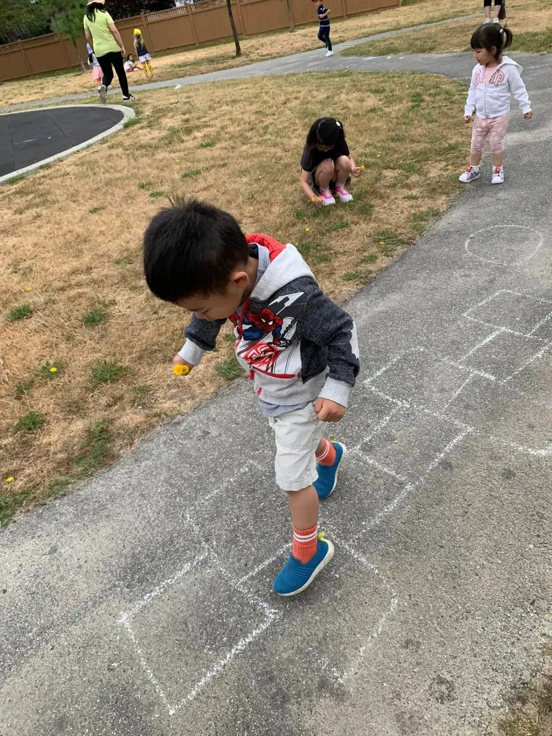 A child running along a chalk hopscotch grid outside