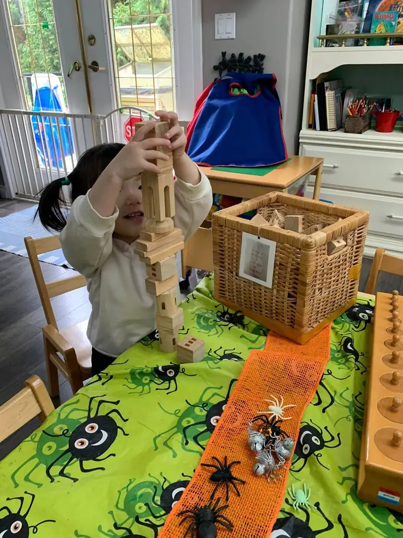 A child carefully stacking wooden blocks into a tall tower