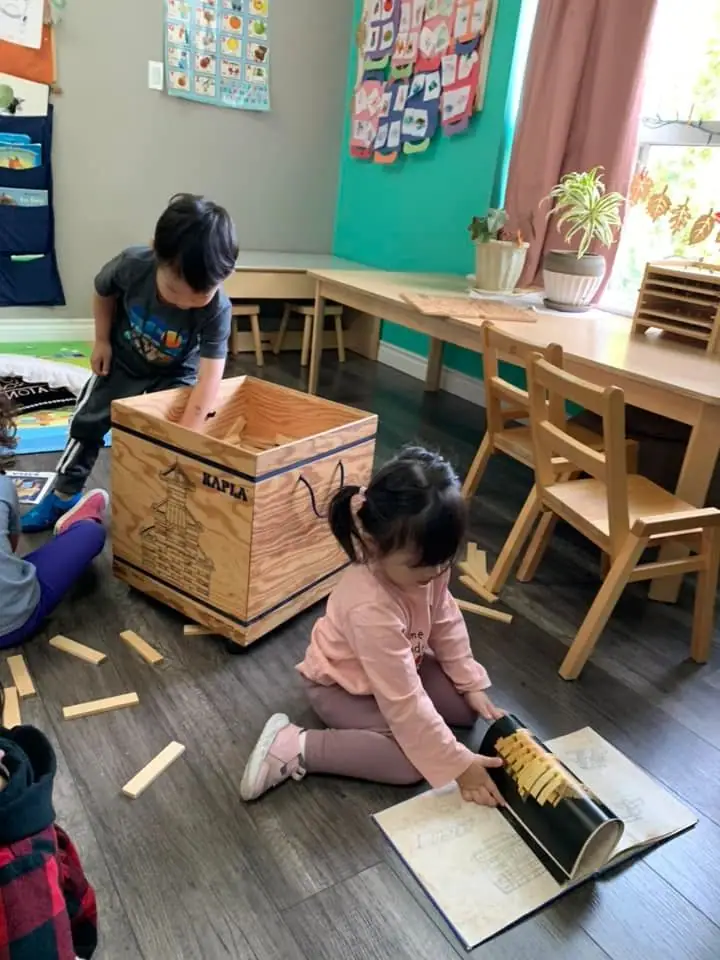 Children lifting wooden planks out of a big block crate