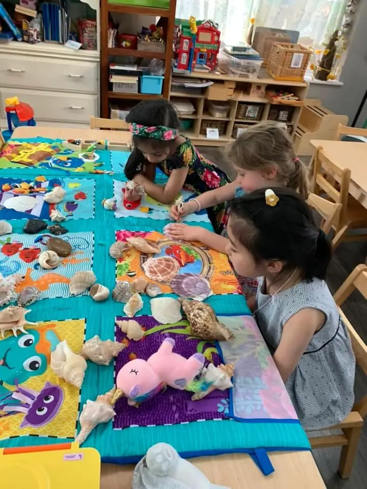 Children playing with soft toys spread across a colourful play mat