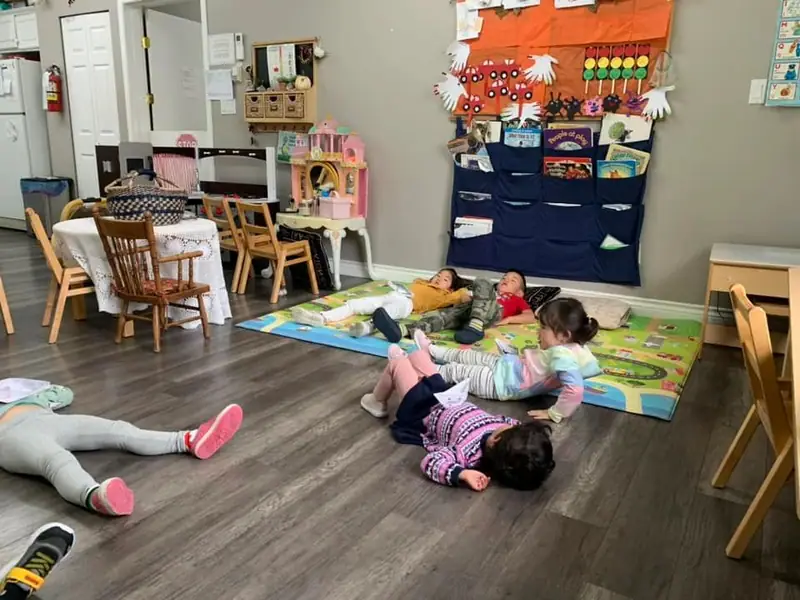 Children stretched out on the play mat in the autumn-decorated room