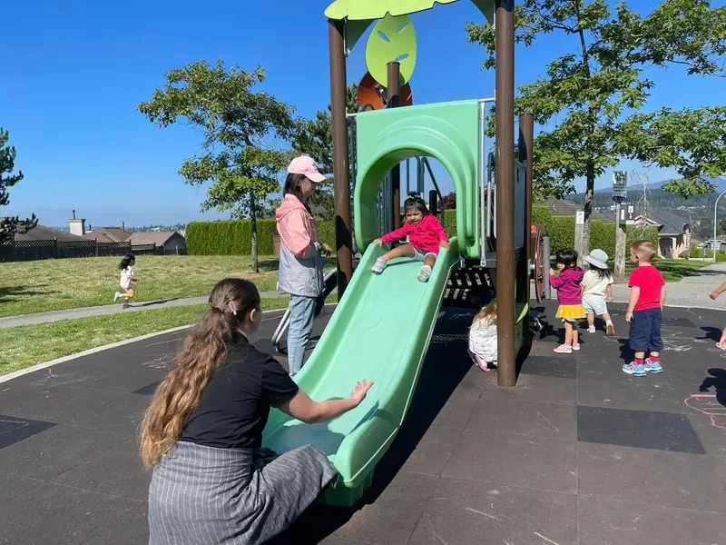 Children and educators at the green slide in the neighbourhood playground