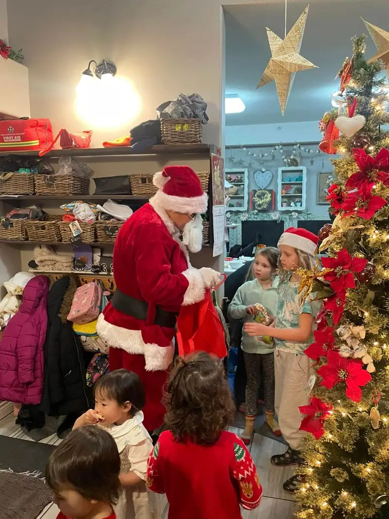 Children meeting Santa beside the Christmas tree in the classroom