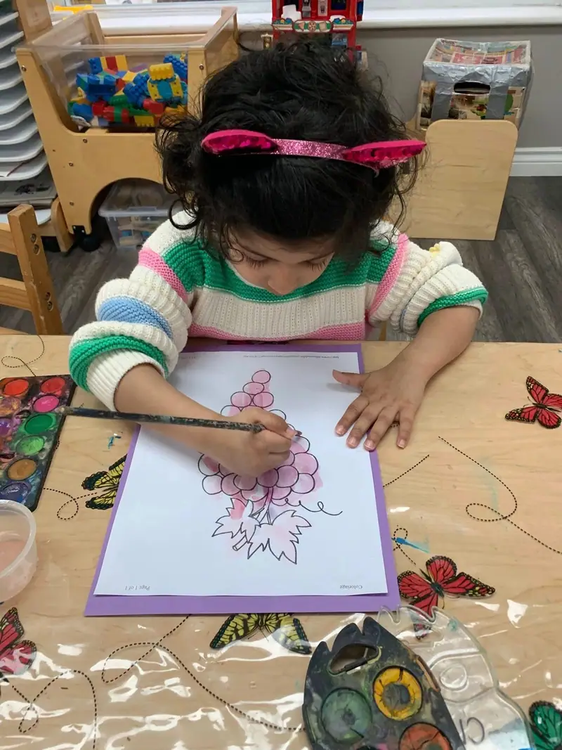 A child painting a butterfly picture with a fine brush