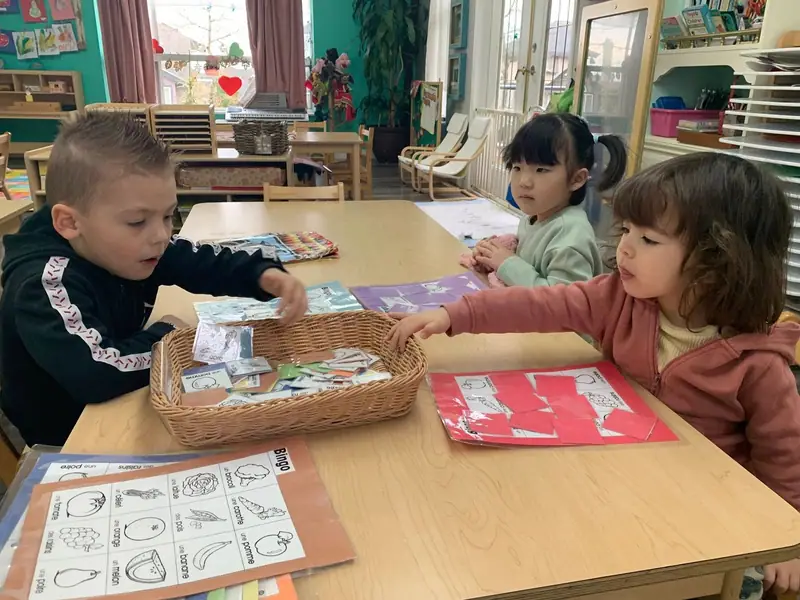 Children working with picture cards and a woven basket at the table