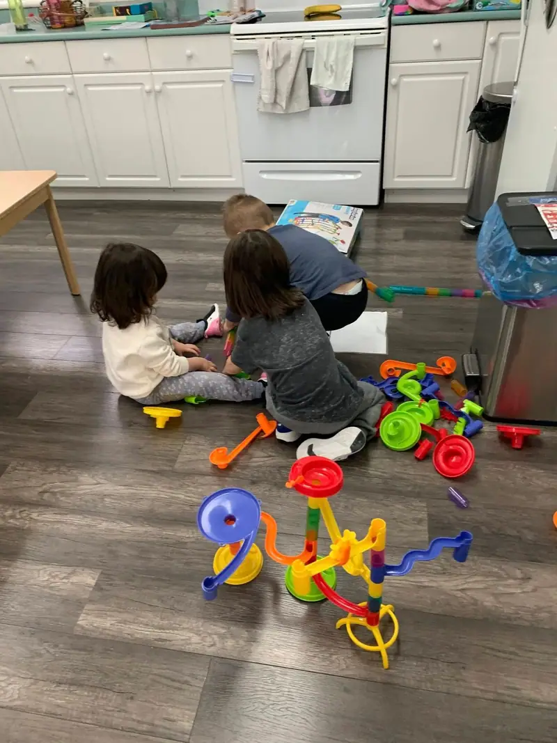 Children playing with a marble run and building toys on the floor