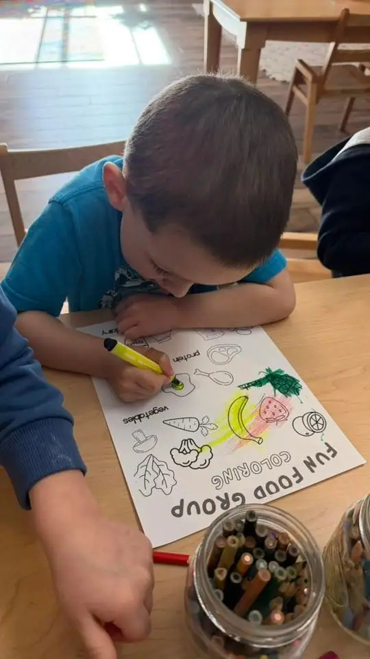 A child colouring in a food-group worksheet