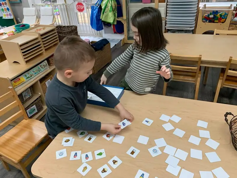 Two children matching picture cards laid out on a low table