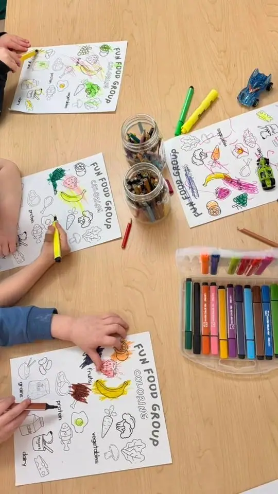 Children colouring food-group worksheets with felt pens