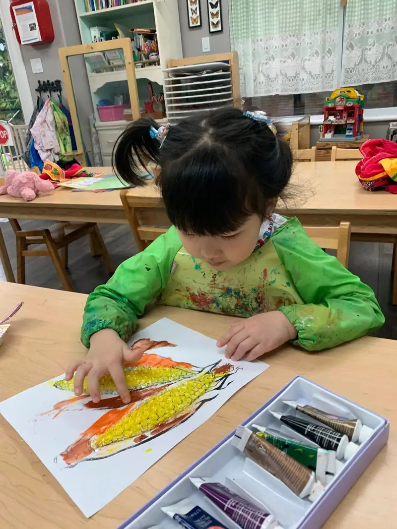 A child colouring a corn cob with wax crayons