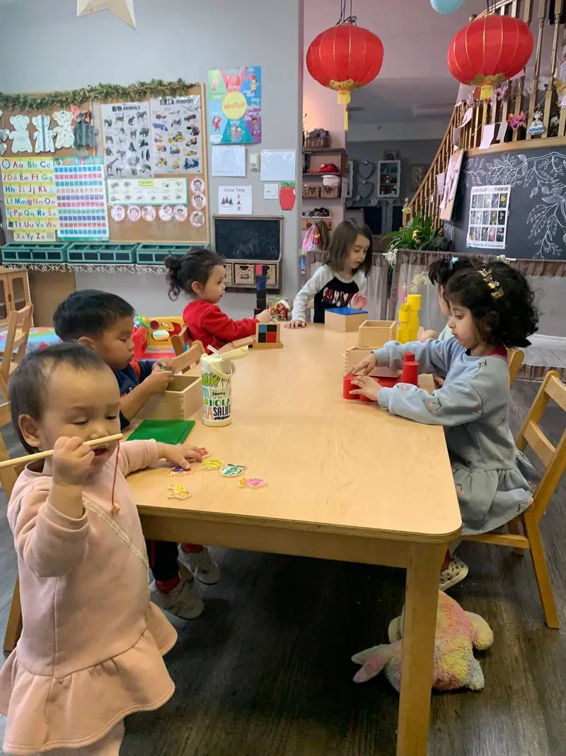 Children painting together at the long table in the art room