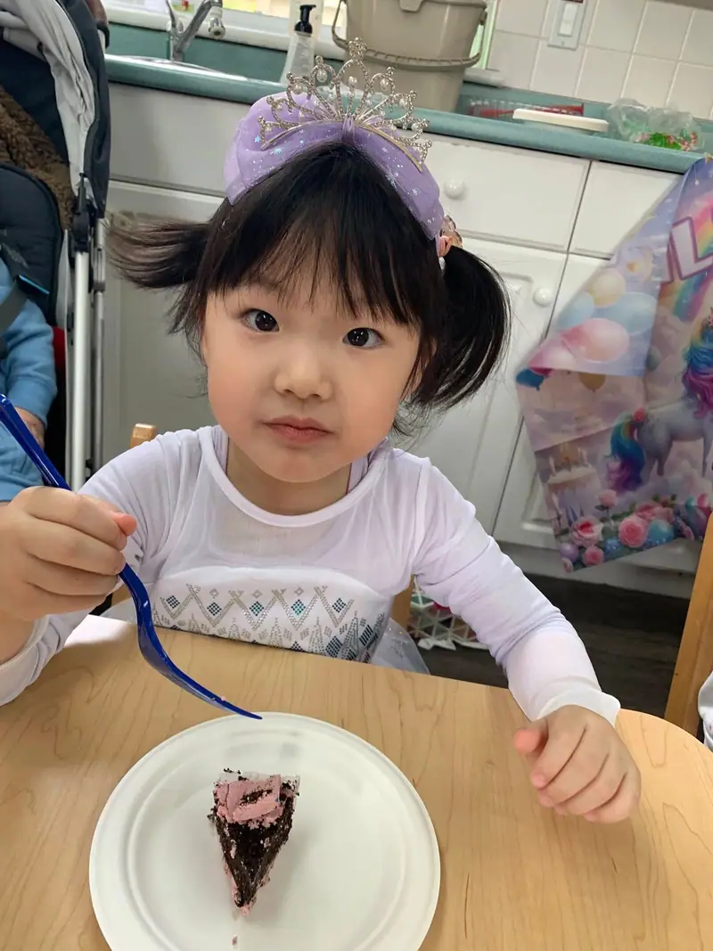 A child holding up a paintbrush at the craft table