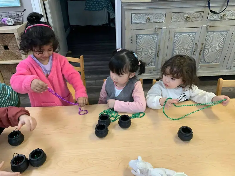 Three children threading a green garland together at the table