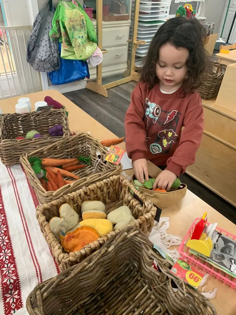 A child sorting felt vegetables out of woven baskets