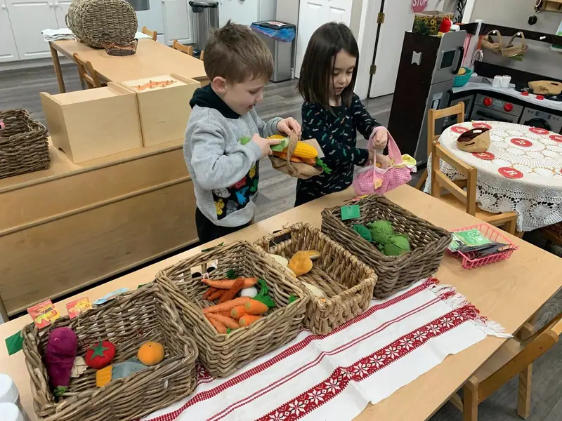 Two children arranging felt produce along a table runner