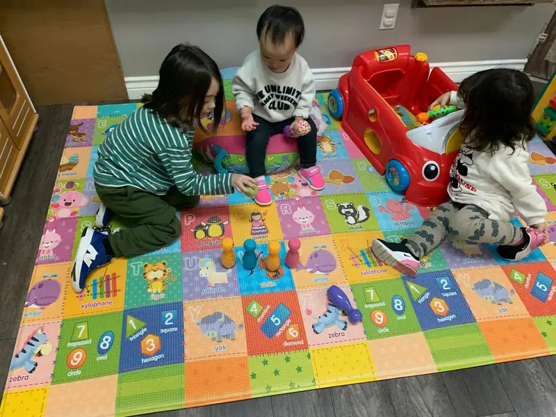 Children playing with a ride-on car on the number play mat