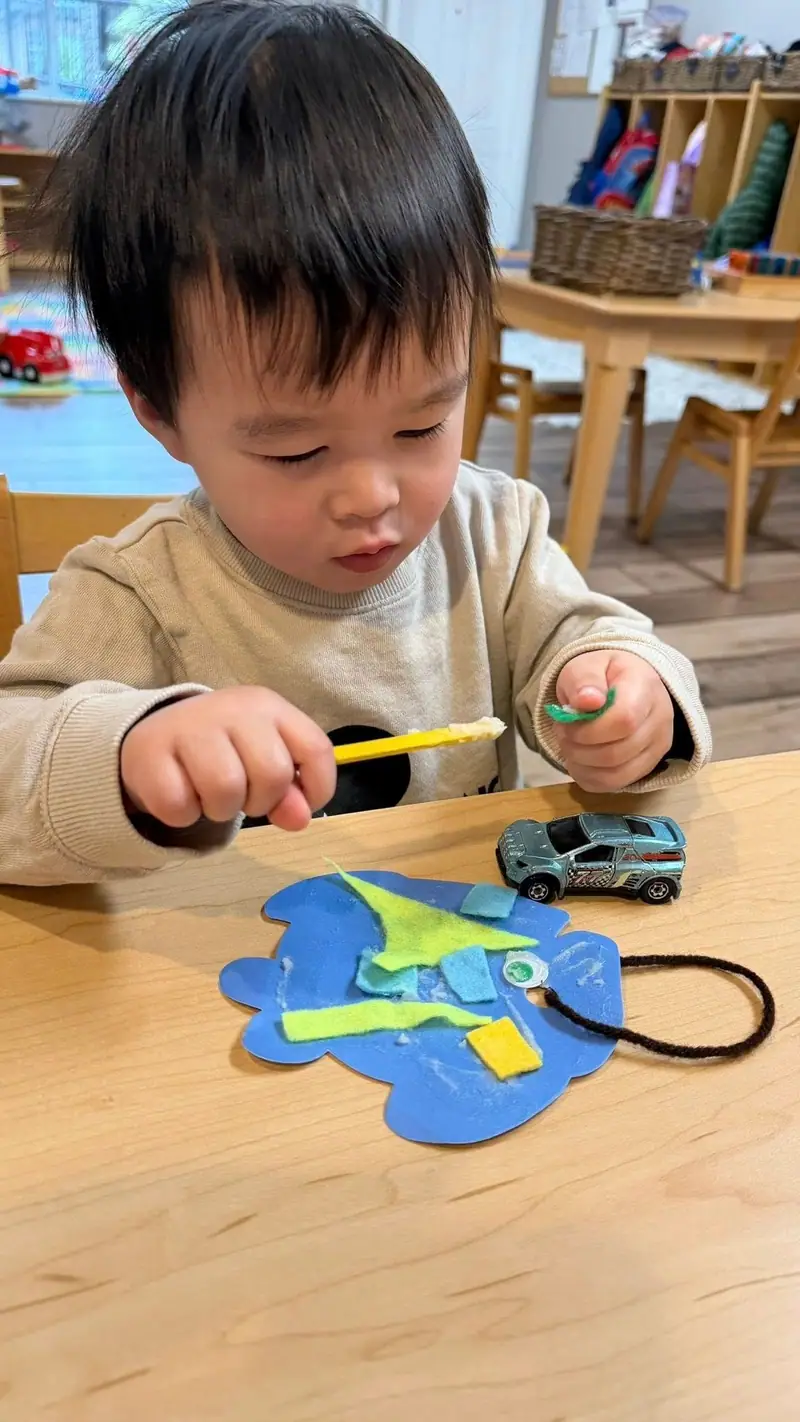 A toddler playing with a felt fish craft and a toy car
