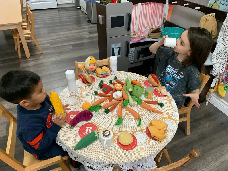 Children setting a round table with play food