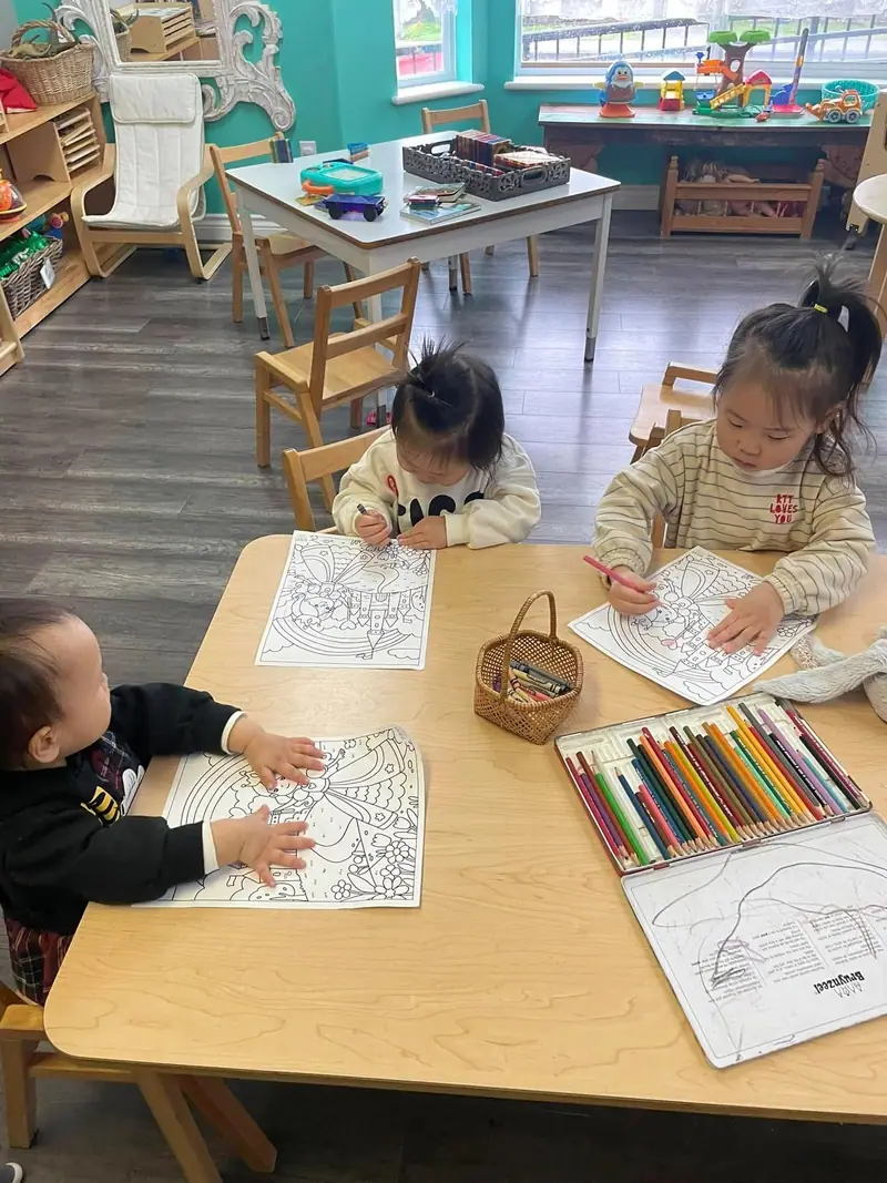 Three children colouring pictures side by side at the table