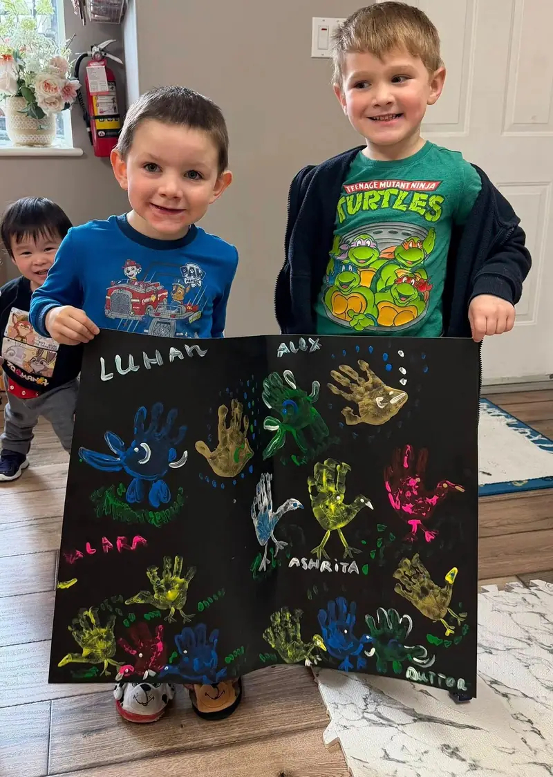 Children proudly holding up their finished handprint artwork