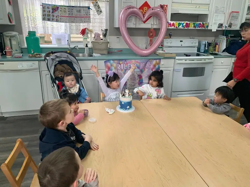 Children gathered around a birthday cake in the kitchen
