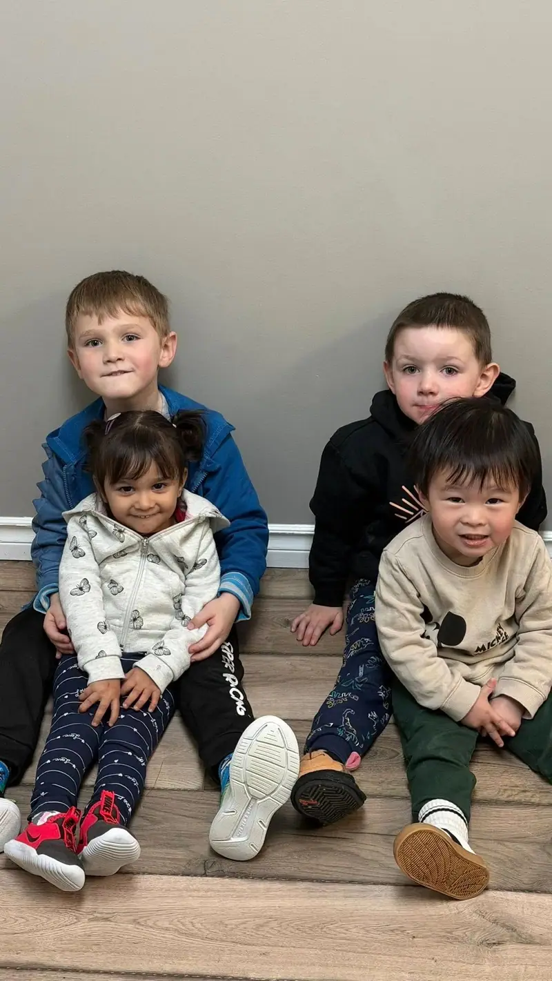 Four children sitting together on the floor for a group photo