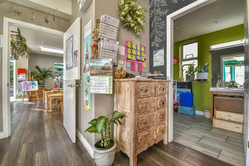An art corner with a wooden dresser, chalkboard and children's work on display