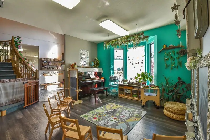 A learning room with a piano, rug and open wooden shelving
