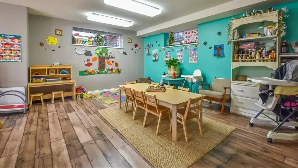 A learning room set up with tables, chairs and a jute rug