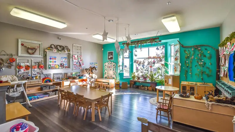 A learning room lined with windows, plants and wooden tables