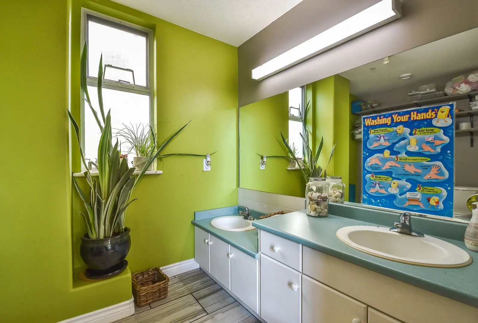A children's washroom with two low sinks and a hand-washing chart