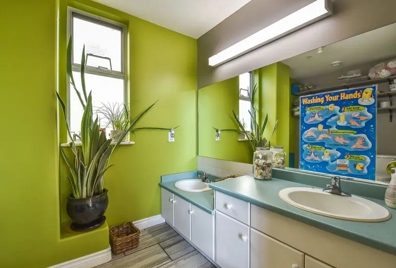 A children's washroom with two low sinks and a hand-washing chart