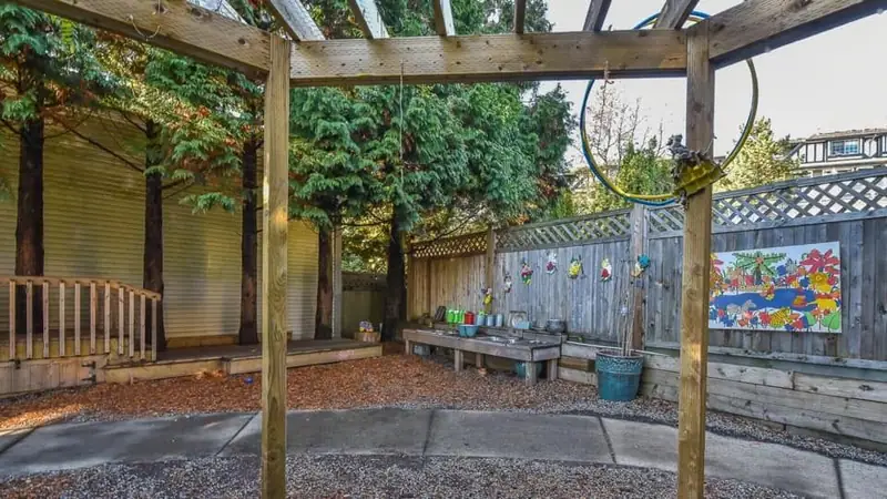 An outdoor mud kitchen and water play bench under the pergola
