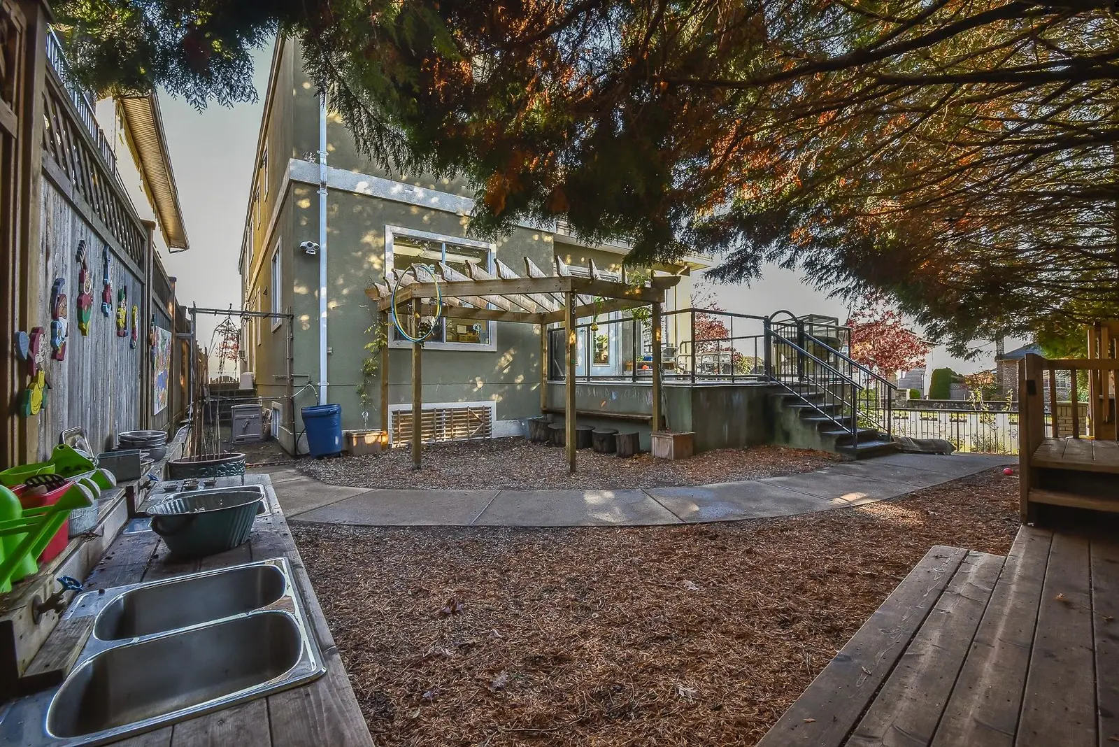 The back yard, with its pergola, bark-mulch surface and mature trees