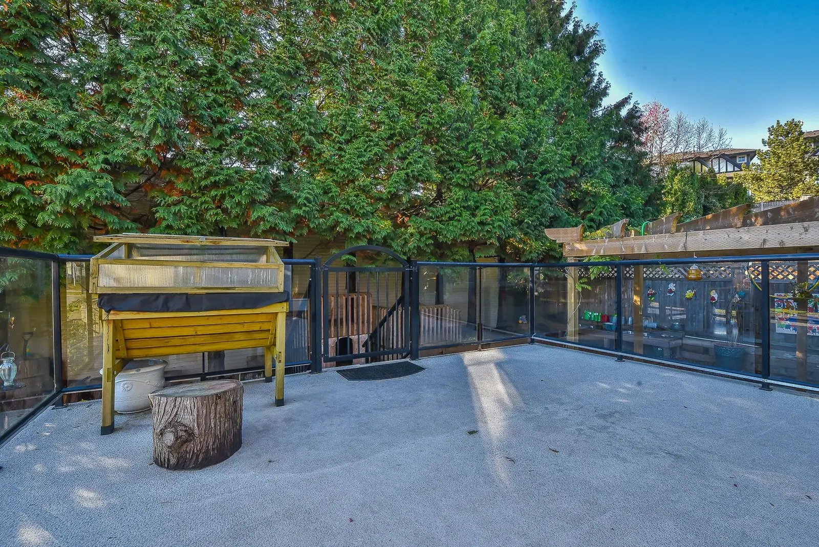 An outdoor play area with climbing equipment and a fenced garden